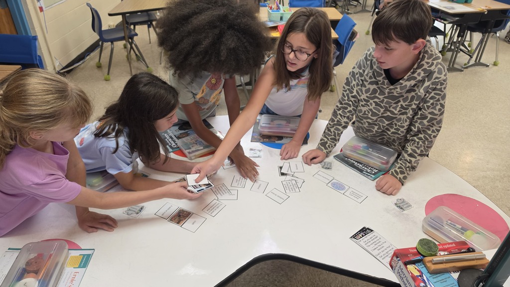 A group of 5 students (1 boy and 4 girls) are working as a team to match vocabulary words to their definitions. 
