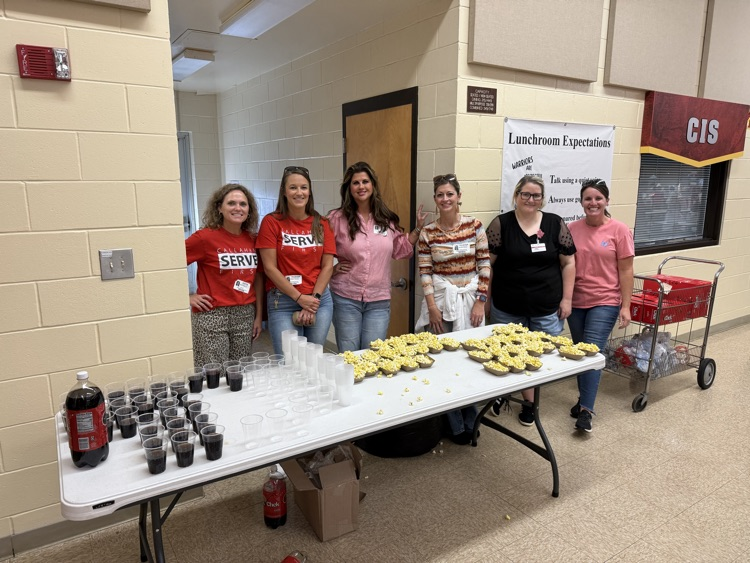 A group of volunteers are ready to serve students popcorn and soda.