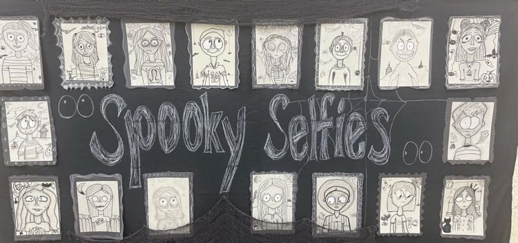  picture of a wall covered in spooky selfies.  students artwork is on black paper  
