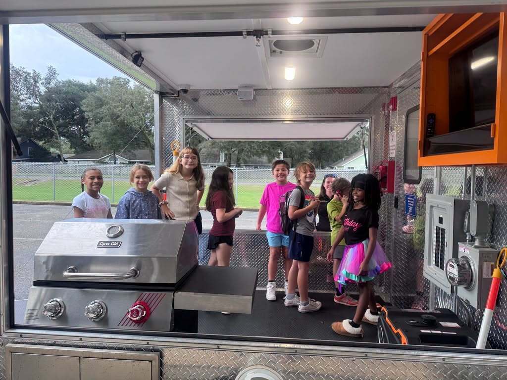 Emma Love Hardee Elementary School students explore the interior of a fire safety simulator during a hands-on fire prevention lesson.