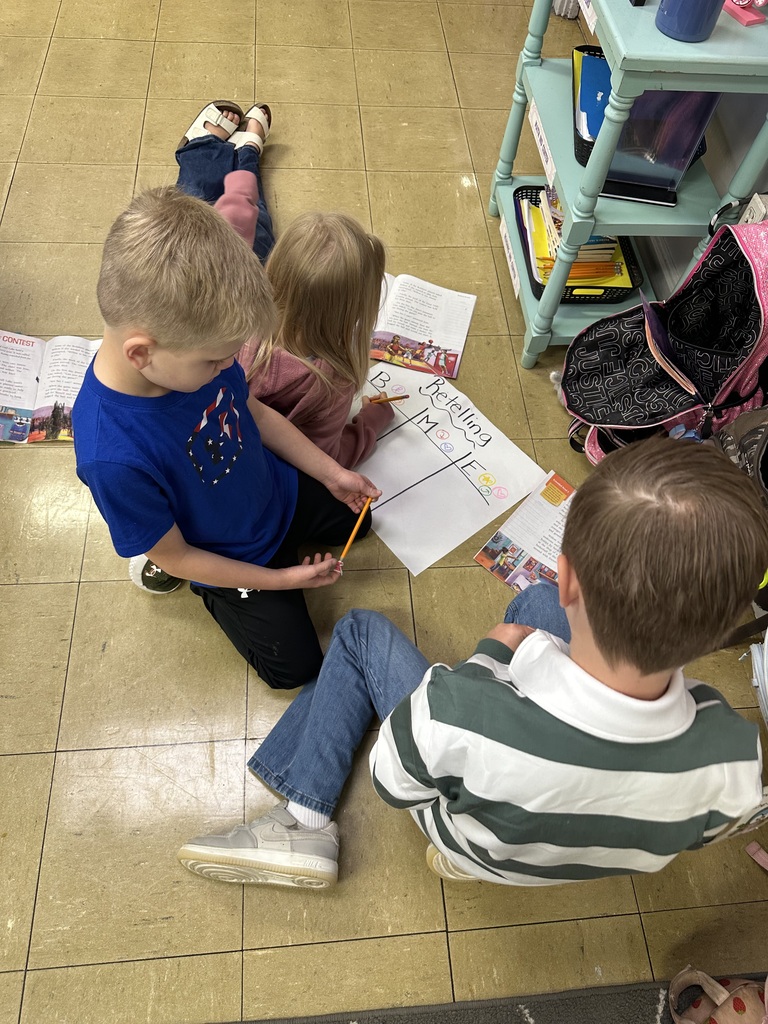students working together on the floor to fill in a retelling chart