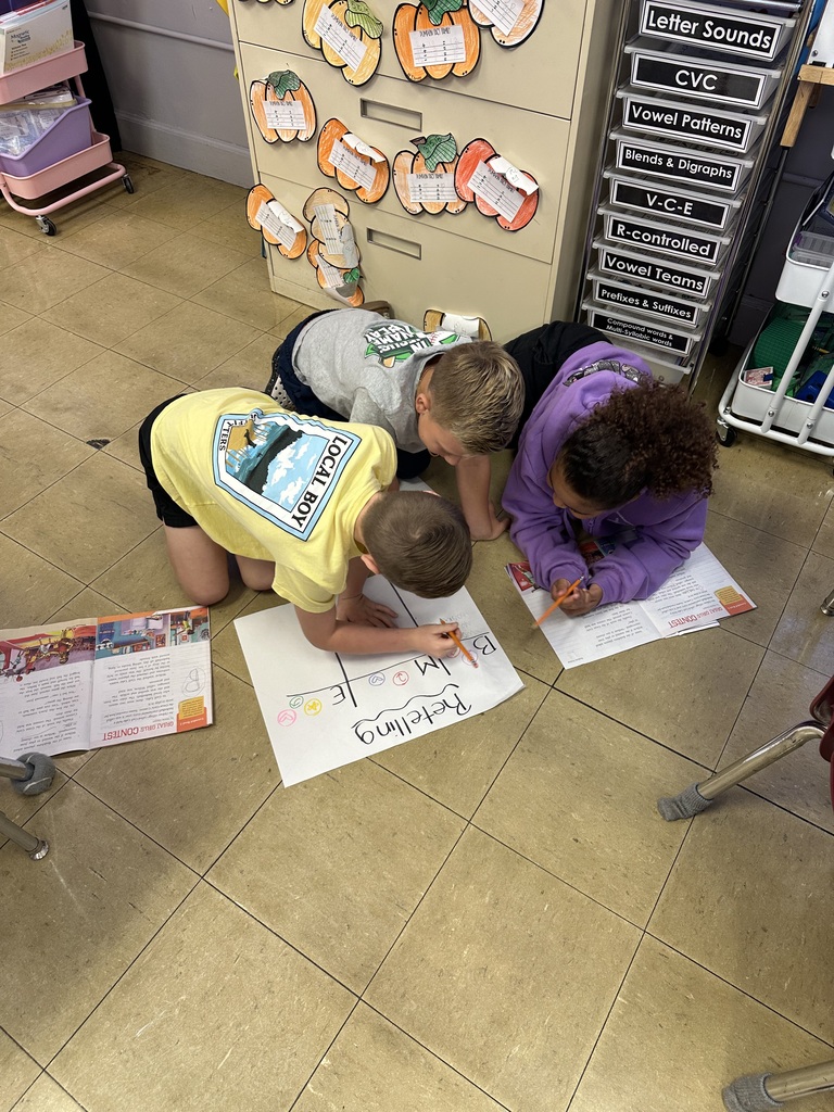 students working together on the floor to fill in a retelling chart