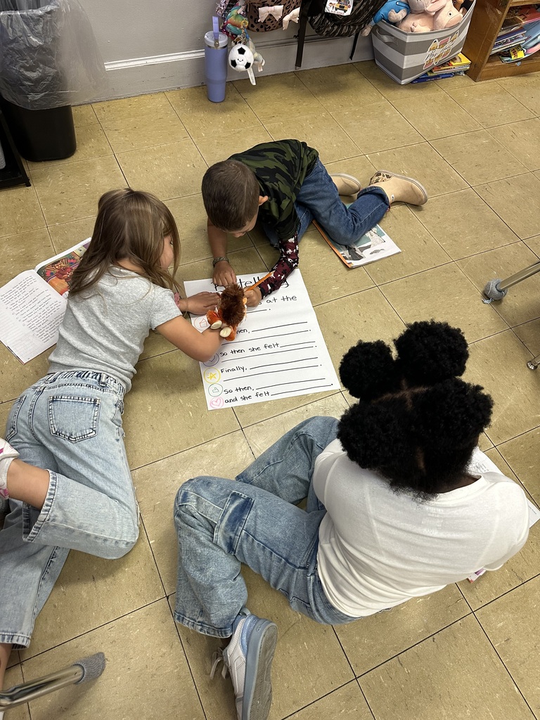 students working together on the floor to fill in a retelling chart