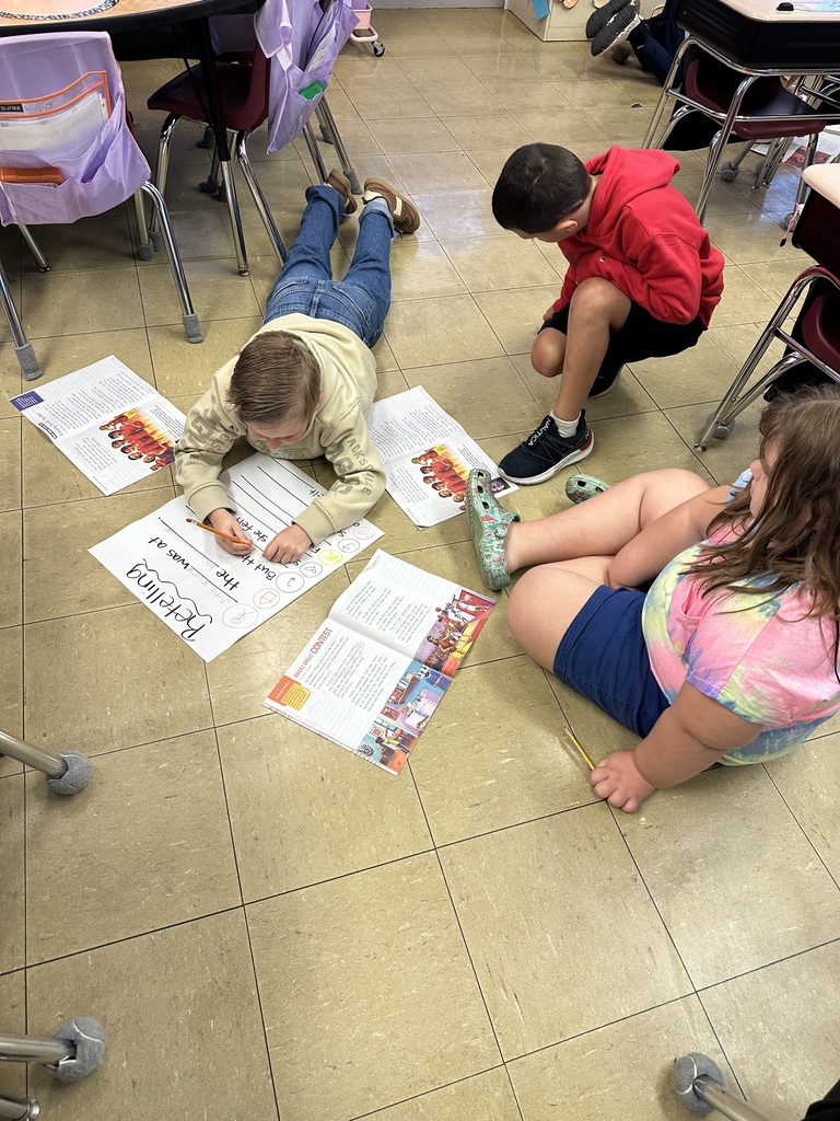 students working together on the floor to fill in a retelling chart