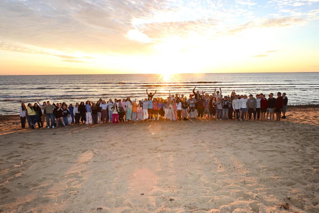 nauset seniors pose together on the beach at sunrise