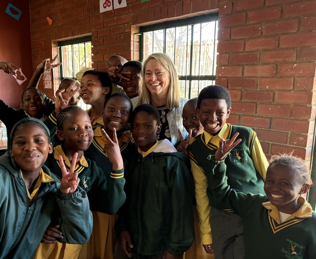 teacher poses with students in south africa