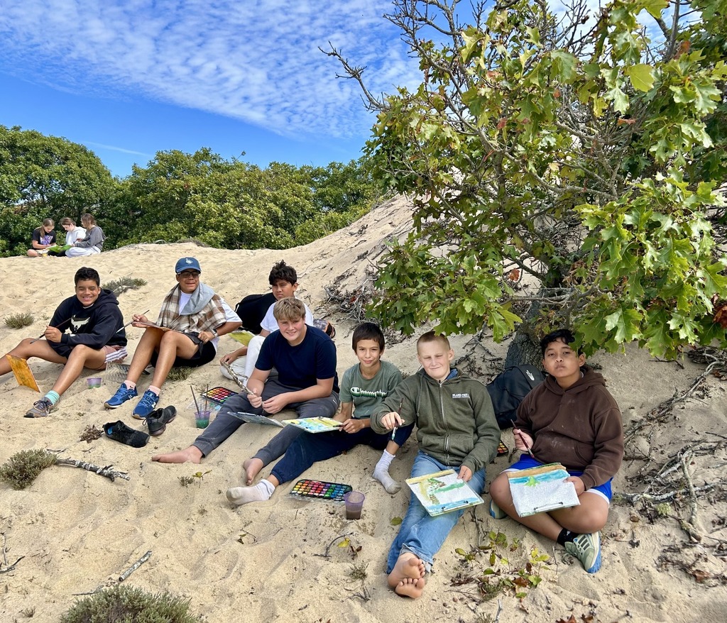 students paint pictures in a sand dune