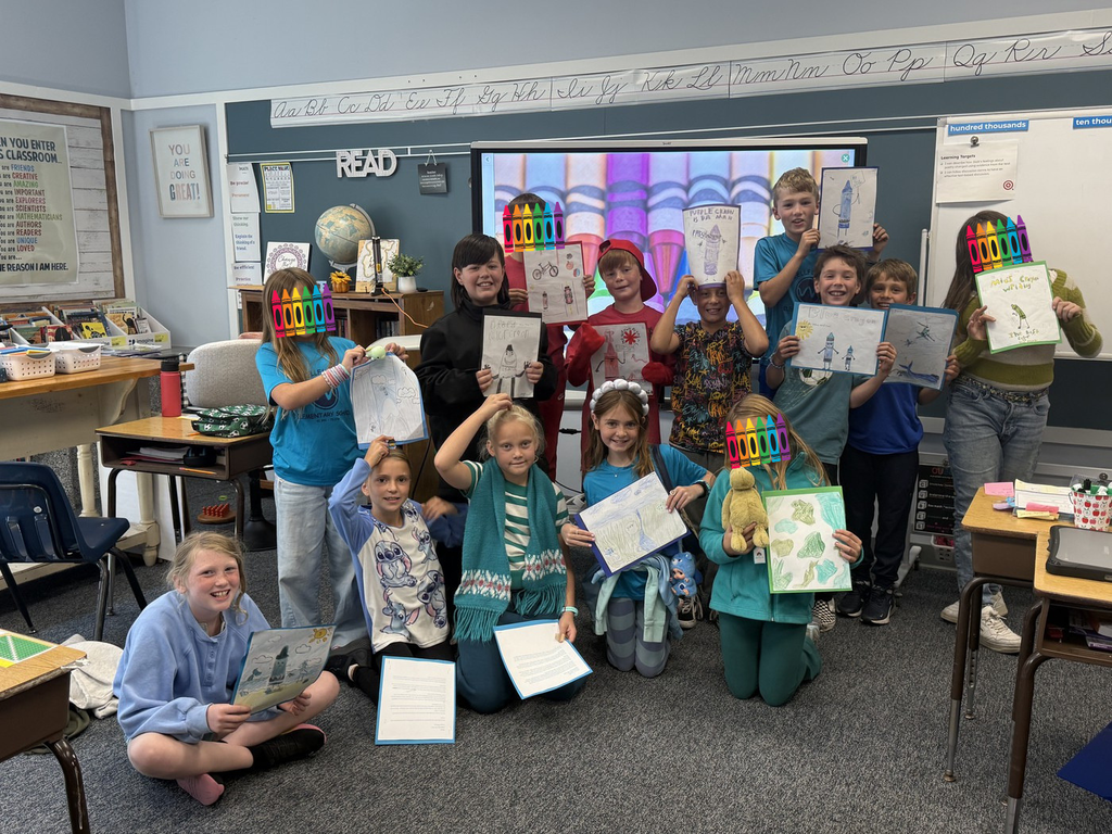 students hold up artwork in classroom