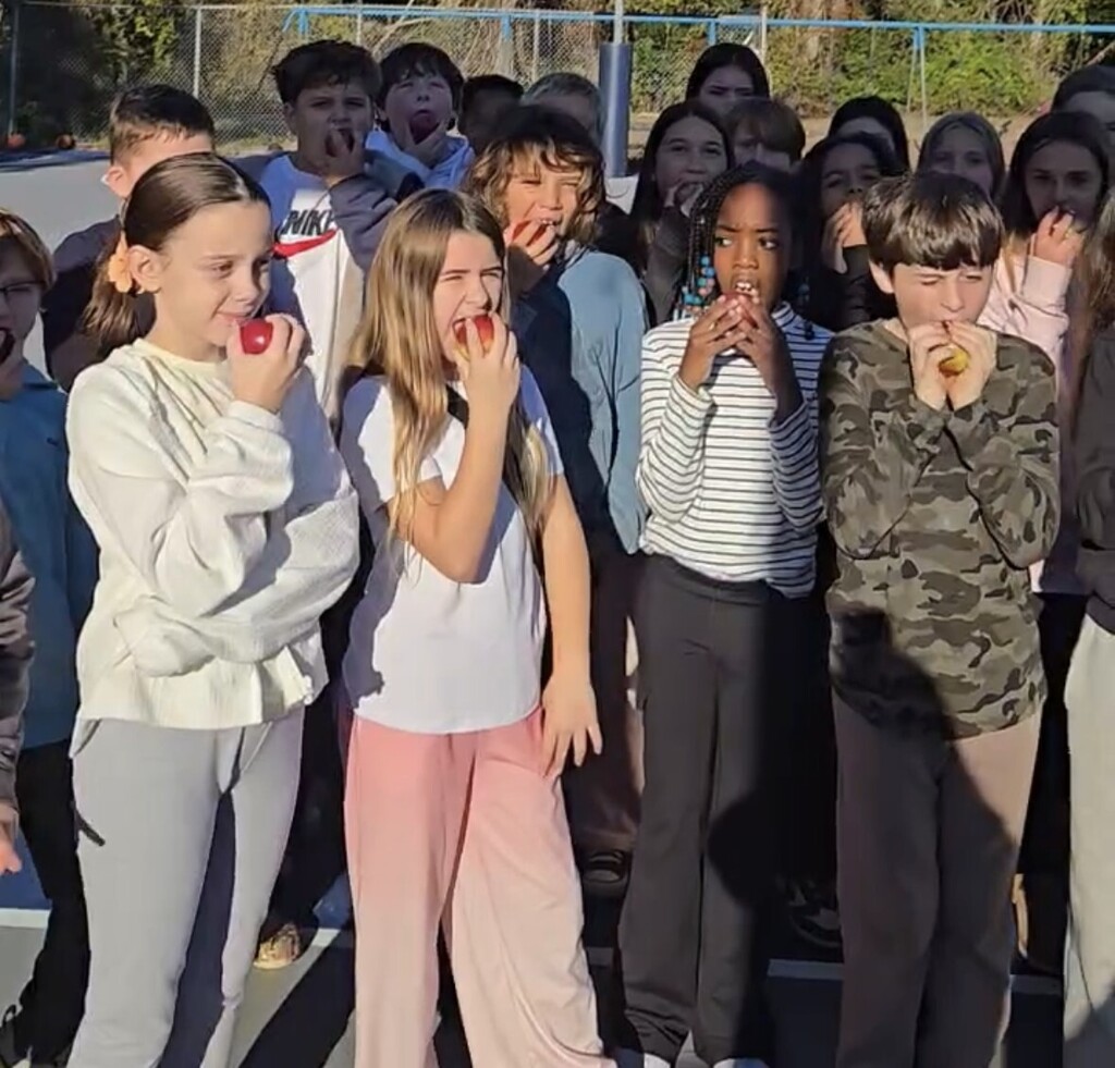 students biting into apples outside