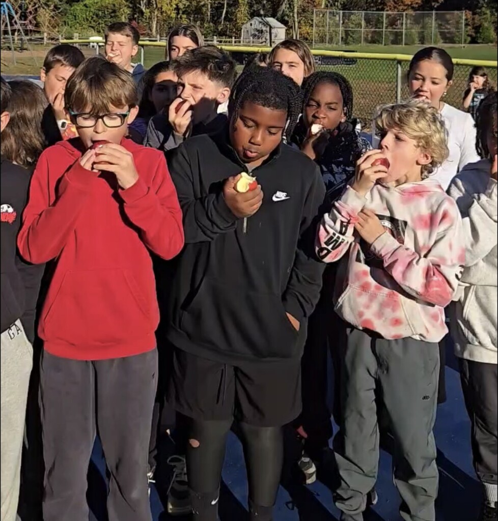 students biting into apples outside