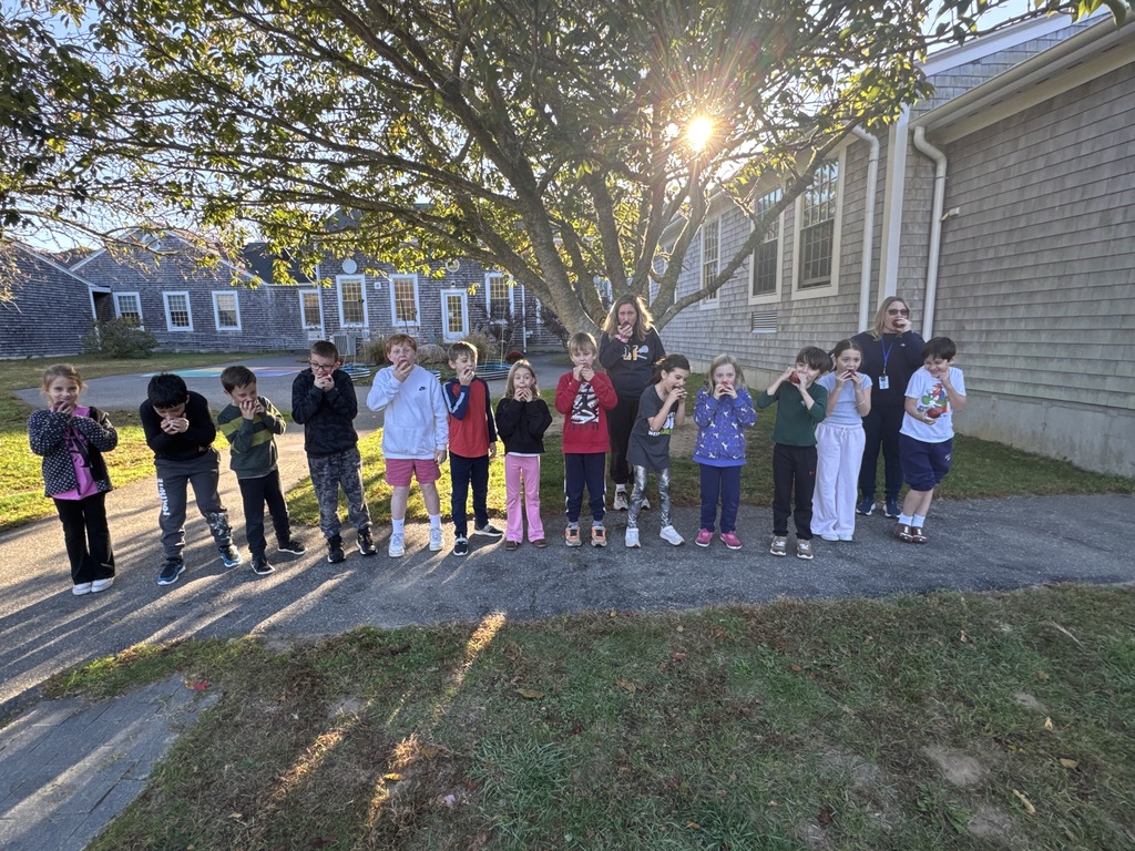 students biting into apples outside