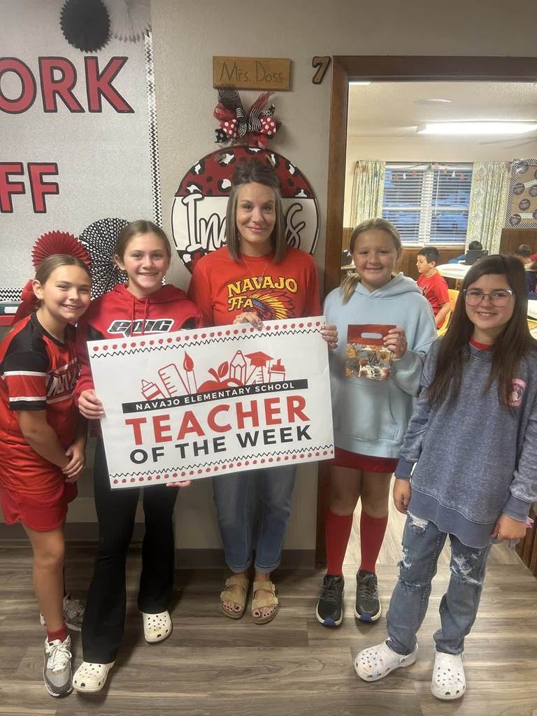 Teacher of the week Mrs. Doss holding a sign with 4 students.