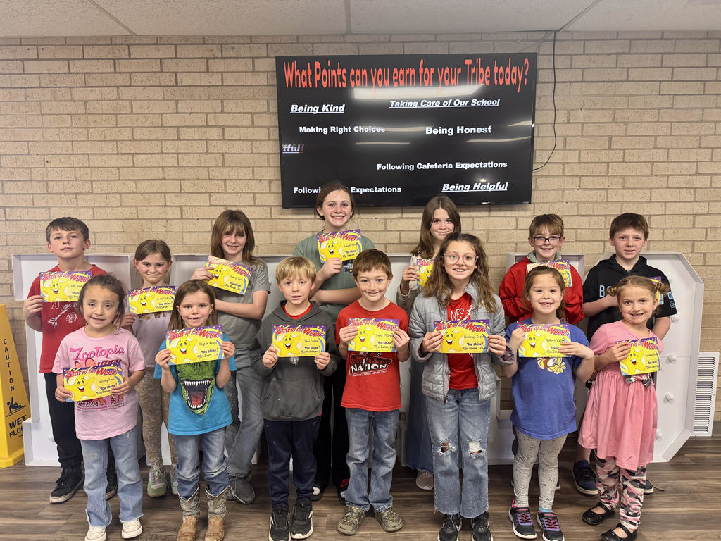 Students of the week standing in the front office holding a yellow certificate.