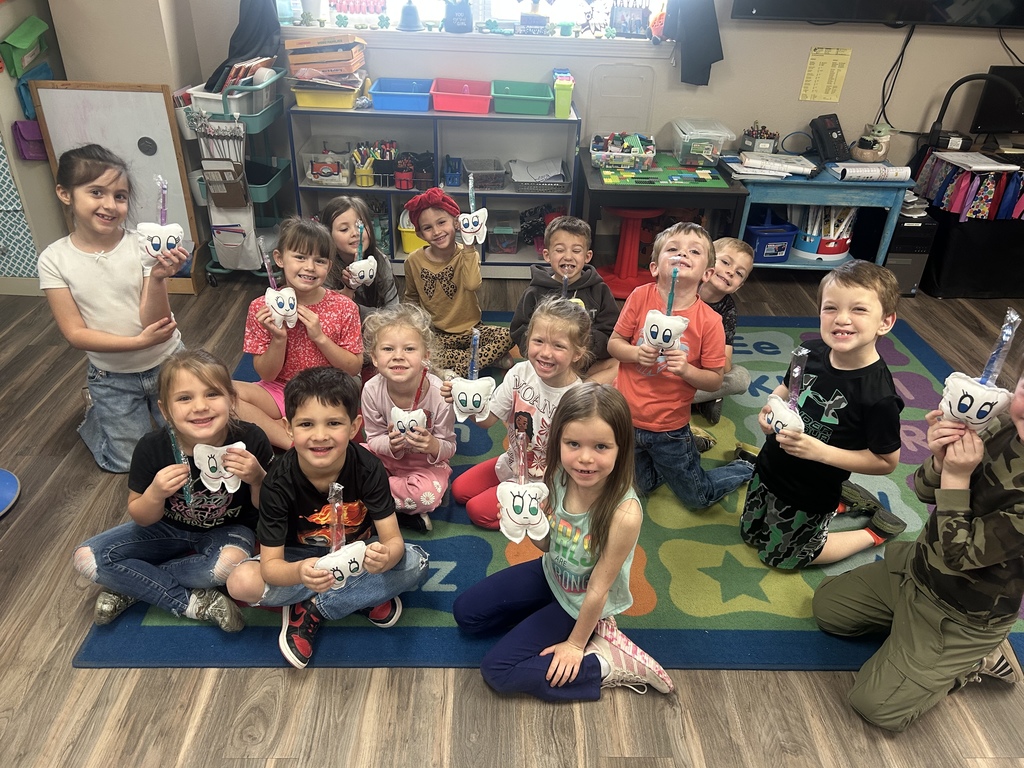 All students sittting down together holding their toothbrush and tooth shaped stuffy