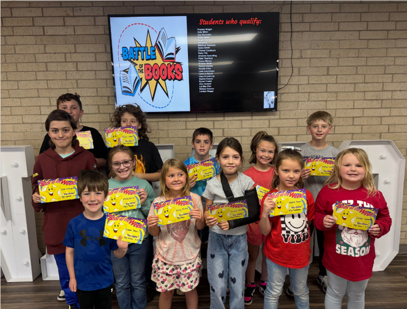 Student of the week standing in the elementary office holding their certificates. 