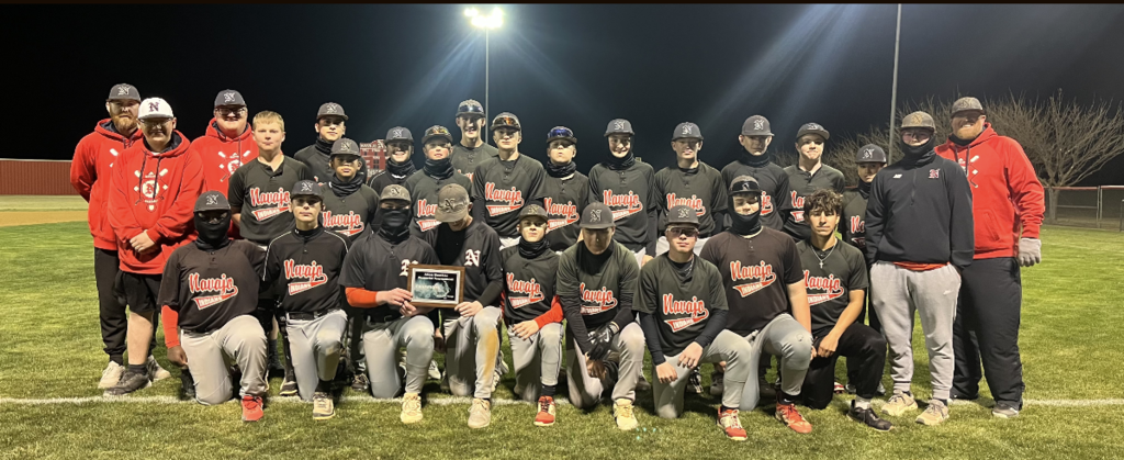 Baseball team posing on the field with coaches next to them, after winning the last game