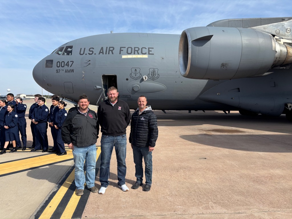 2 board members and the superintendent standing in from of a c-17