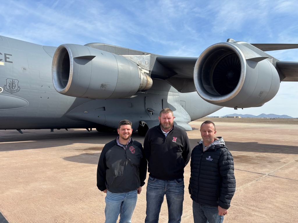 2 board members and the superintendent standing in from of a c-17