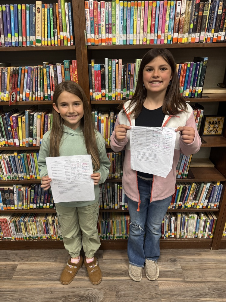 two students holding their completed sign off sheets