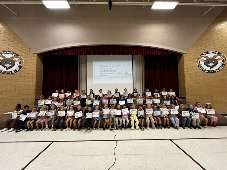 Students sitting on the stage with their certificate of making their mark here at Riverview