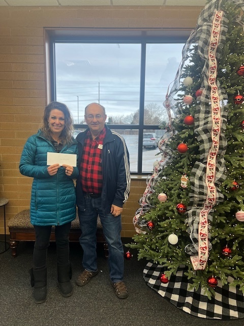 man and principal holding an envelope by a Christmas tree