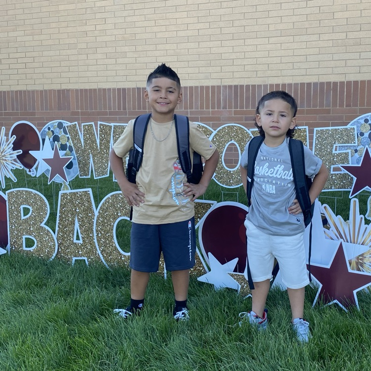 two students standing in front of a sign that says welcome back