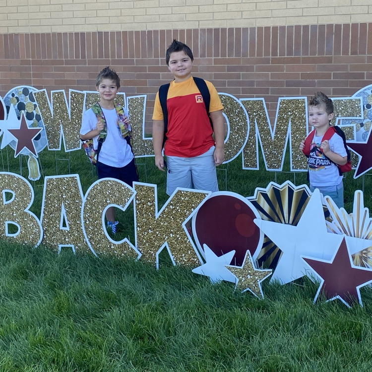 three brothers in front of a welcome back and sign