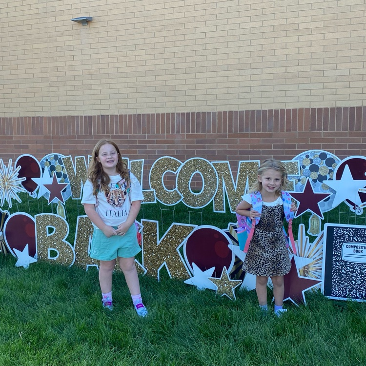 two girls standing next to a welcome sign