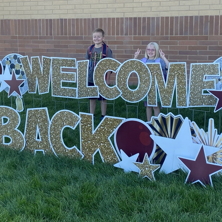 two kids standing next to a welcome sign