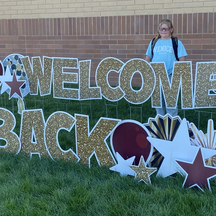 one students standing next to a welcome back sign