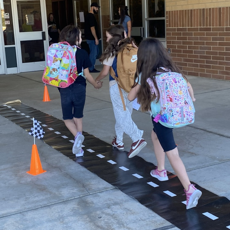 three girls holding hands walking down a road carpet