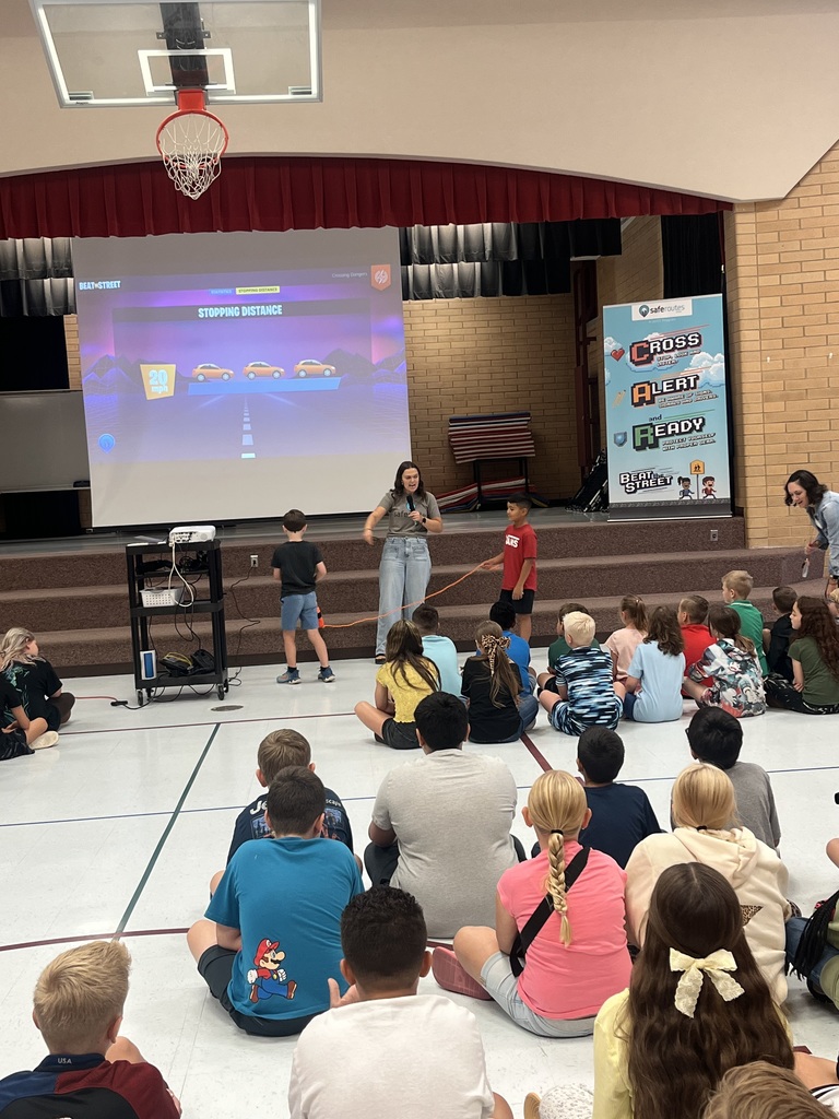 two students participating in a safety demonstration by holding an orange rope; stopping distance is projected onto the screen