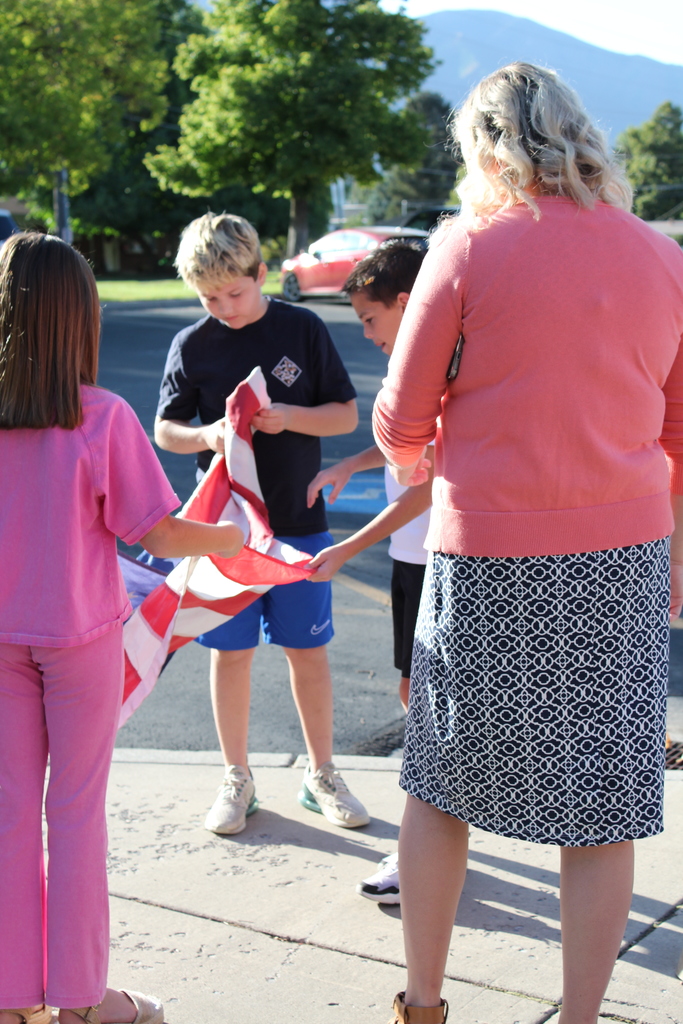 Miss Brown and three students preparing the flag to be raised