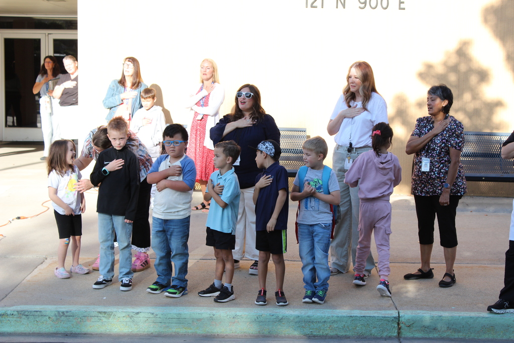 Students and teachers with hands on hearts singing the National Anthem