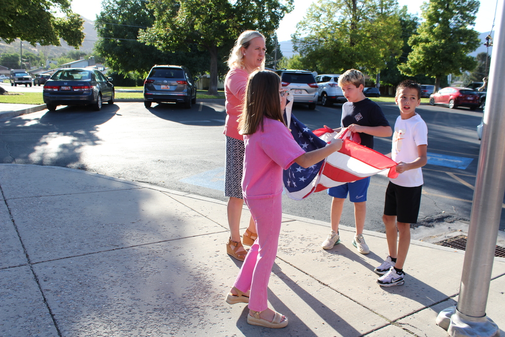Miss Brown and three students preparing the flag to be raised