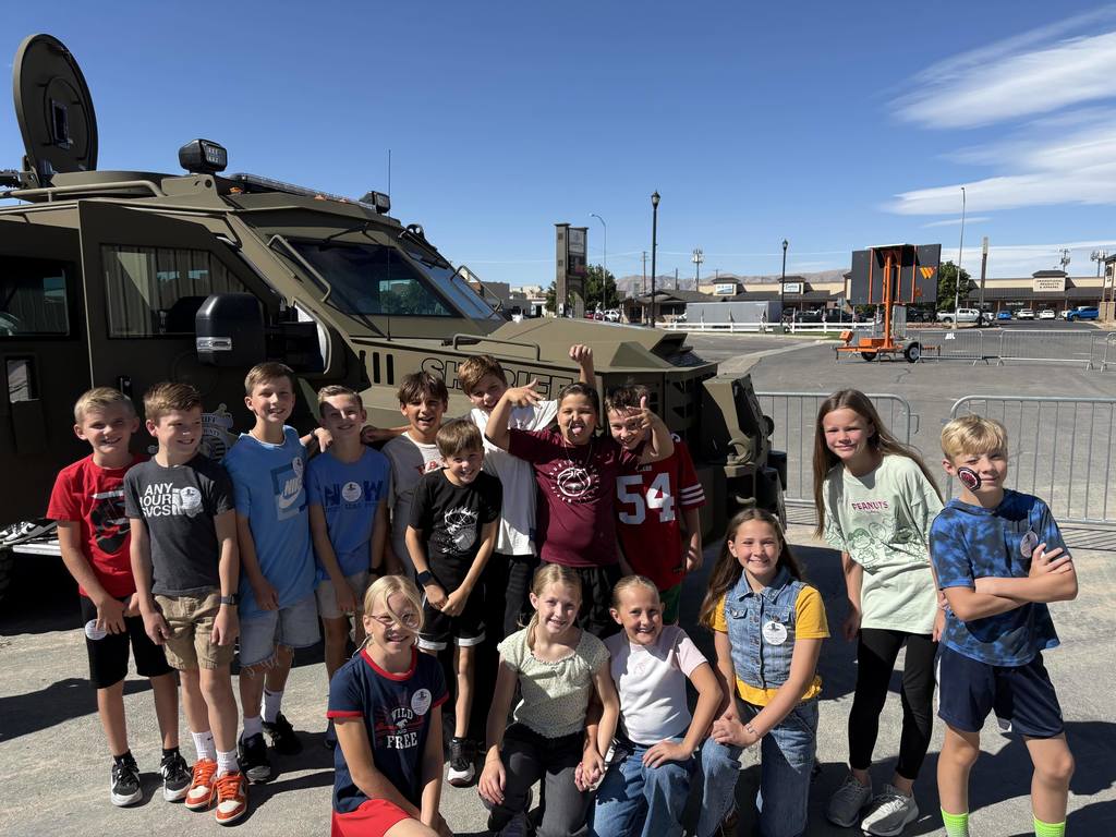 Students in front of a military vehicle at the fairgrounds.