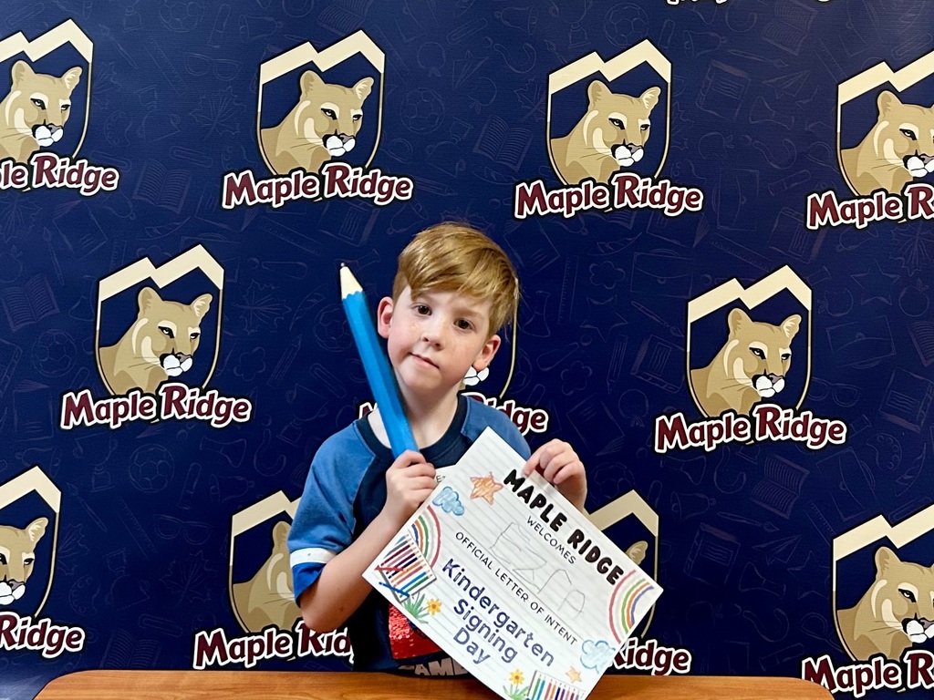 Students in front of a Maple Ridge backdrop holding their "Letter of Intent."