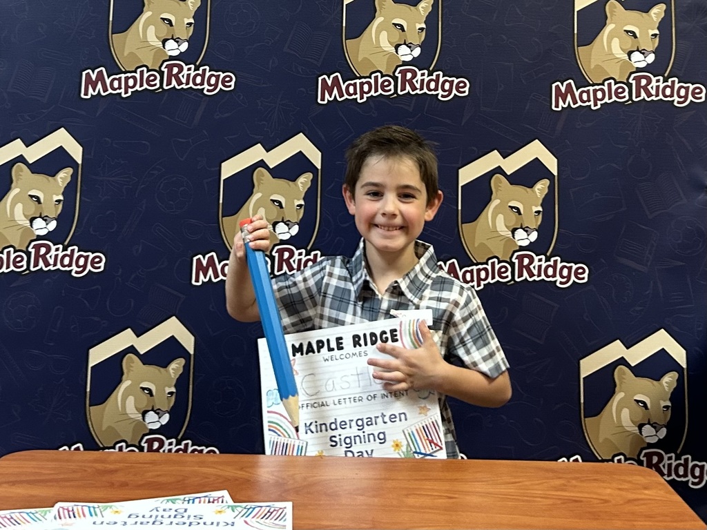Students in front of a Maple Ridge backdrop holding their "Letter of Intent."