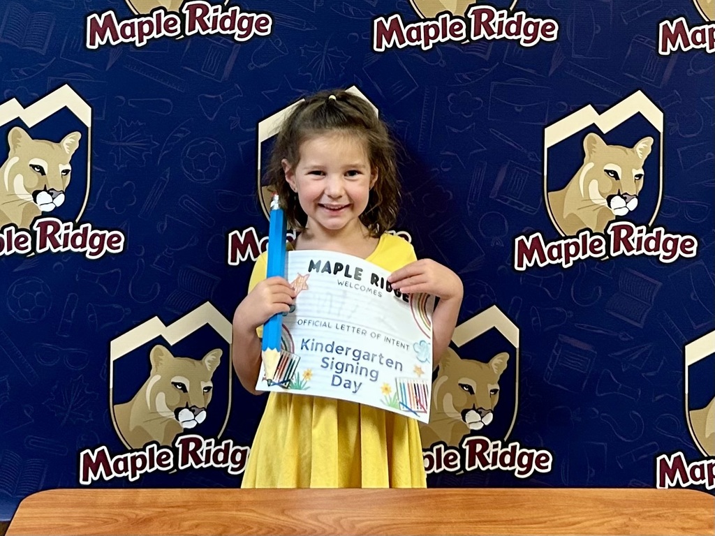 Students in front of a Maple Ridge backdrop holding their "Letter of Intent."