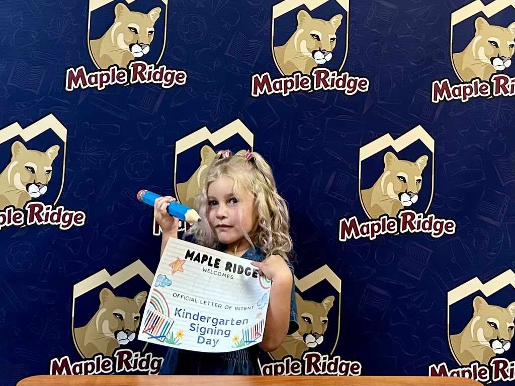 Students in front of a Maple Ridge backdrop holding their "Letter of Intent."