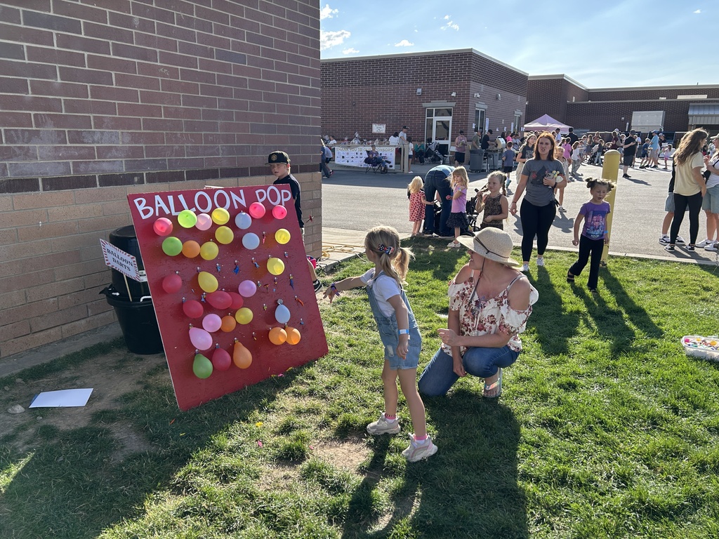 Student throwing darts at balloons.