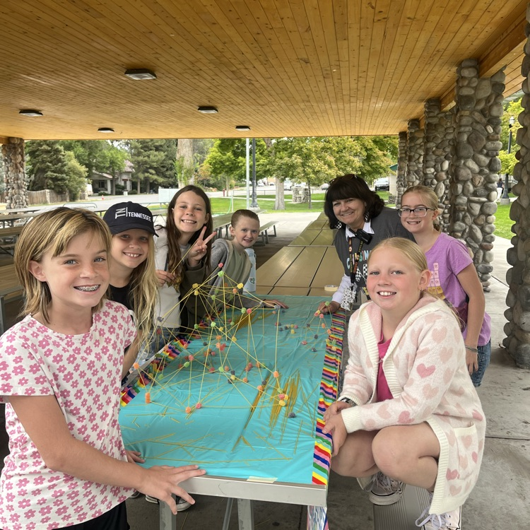 a group of girls posing with a tower that they built out of spaghetti and play dough