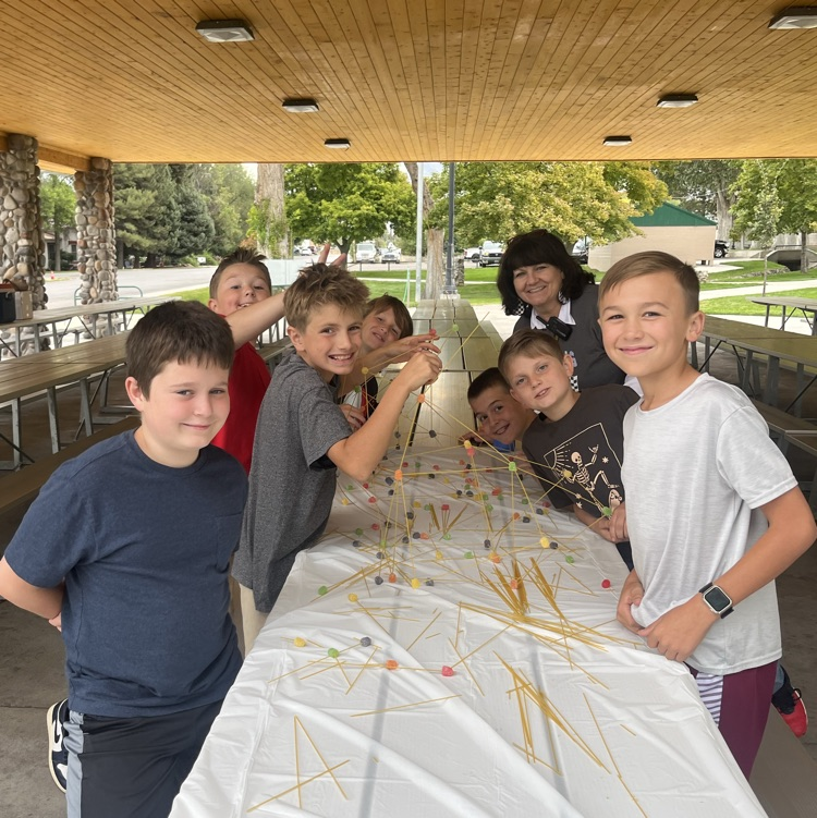a group of students posing with a tower that they built with spaghetti and play dough