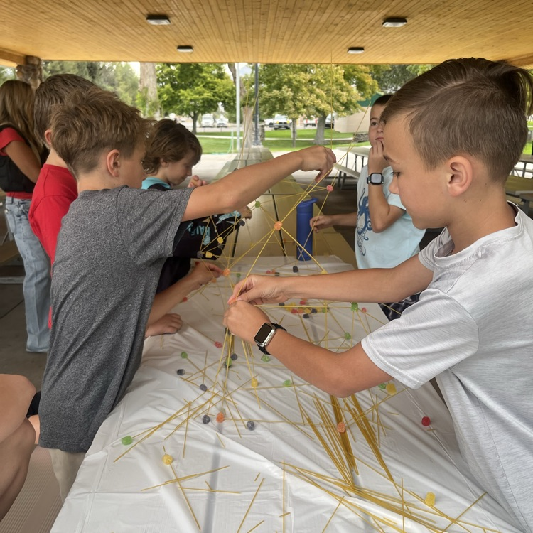 a group of students building a tower with spaghetti and play dough