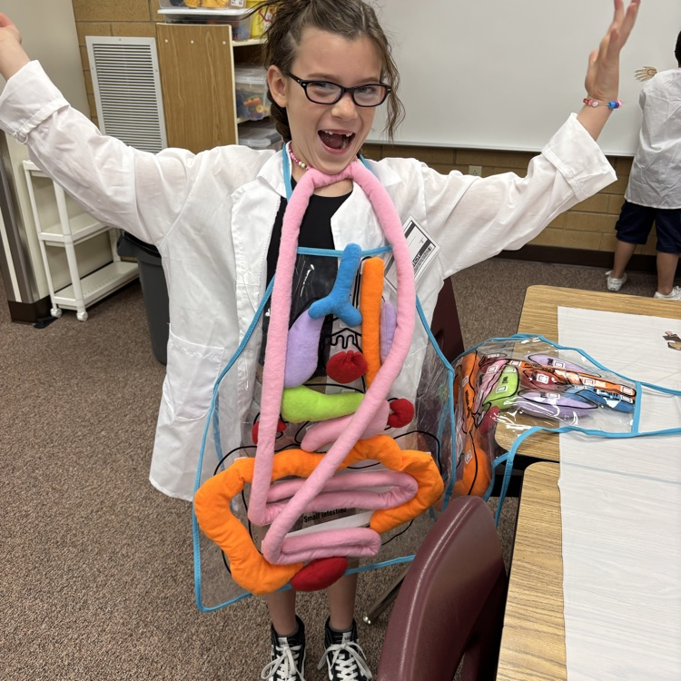a student with arms in the air holding up a stuffed organ system with her chin