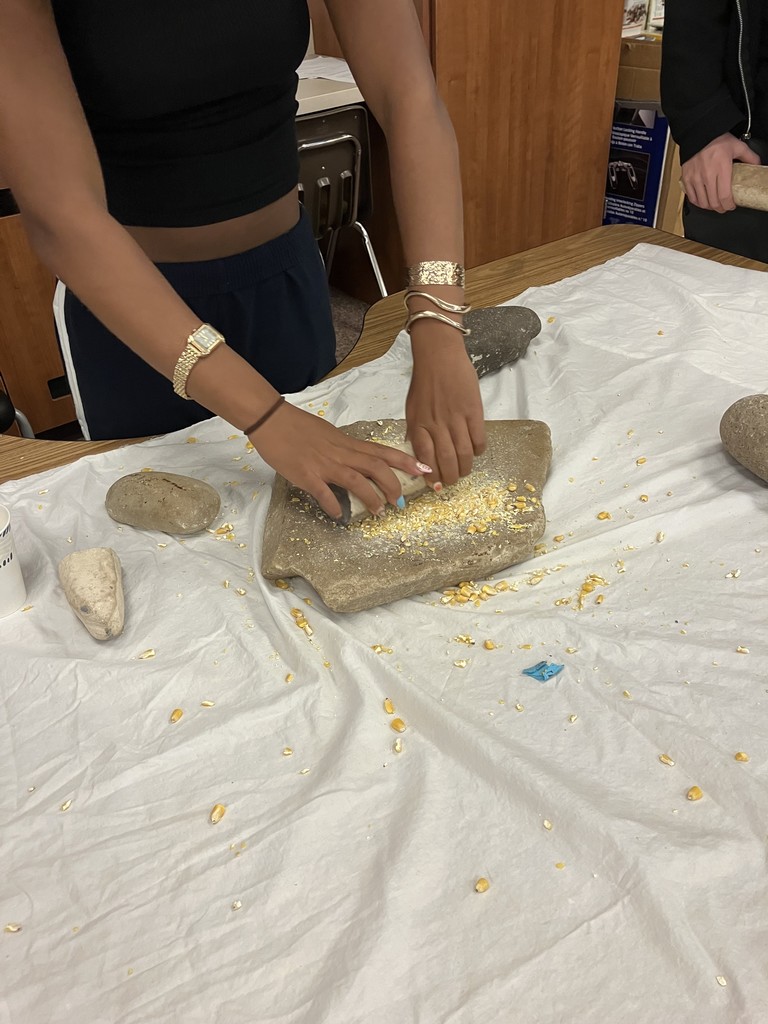 Grinding corn to better understand the culture of ancient tribal groups while in US History.
