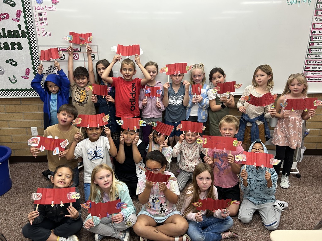Second graders holding up their artwork