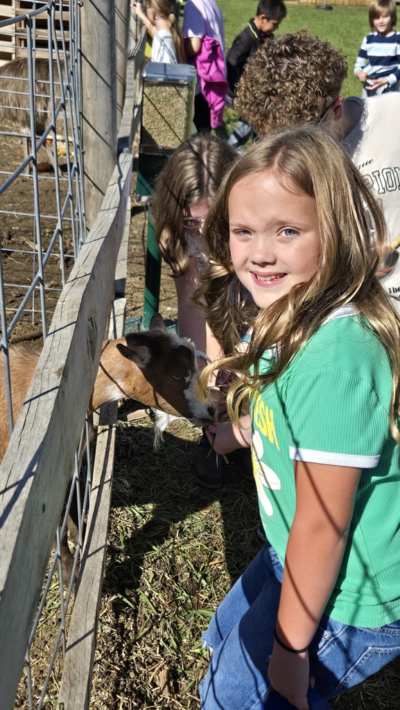 three students petting a goat through a fence