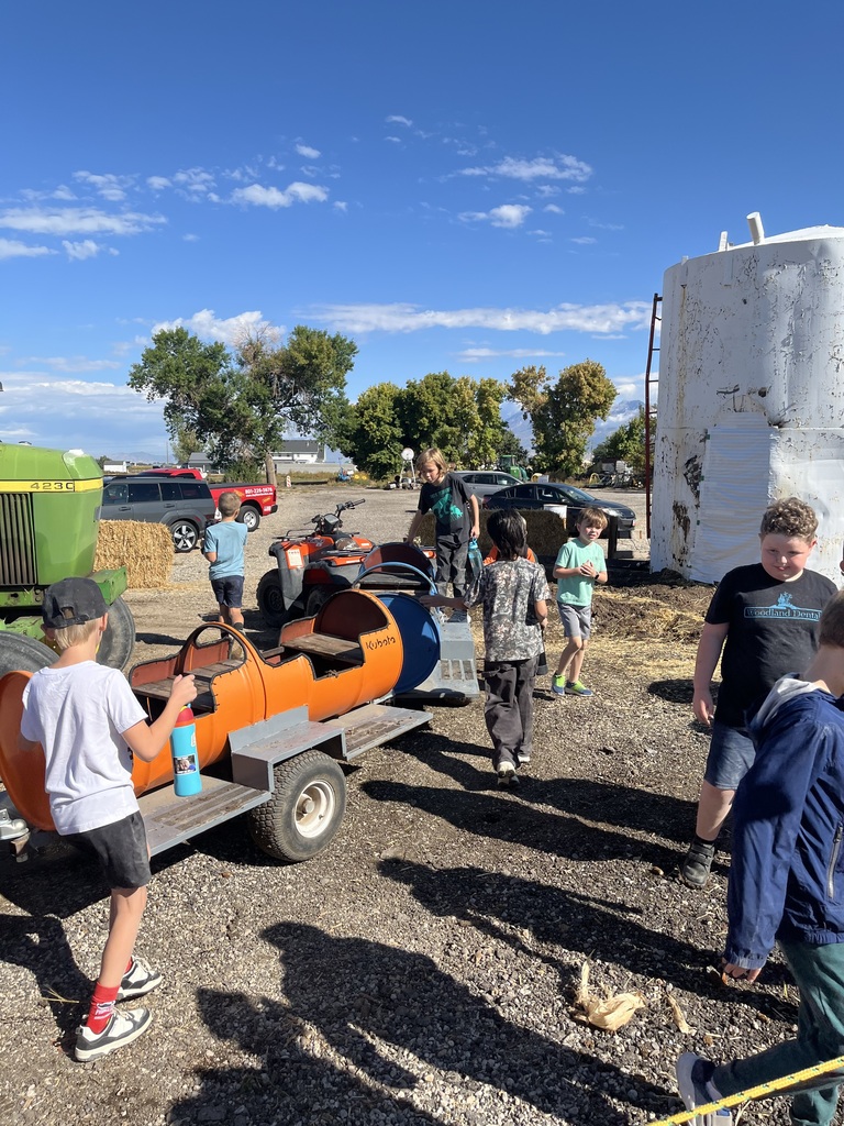 a group of kids playing on/around a train that is pulled by a four wheeler