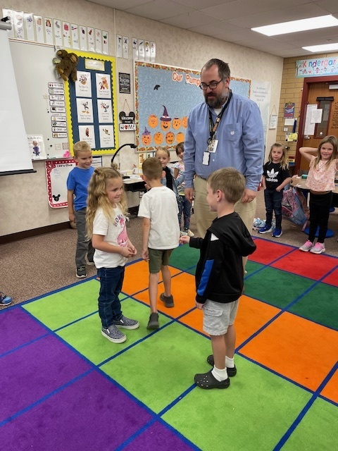 pairs of kindergarten students acting while a drama specialist watches over them